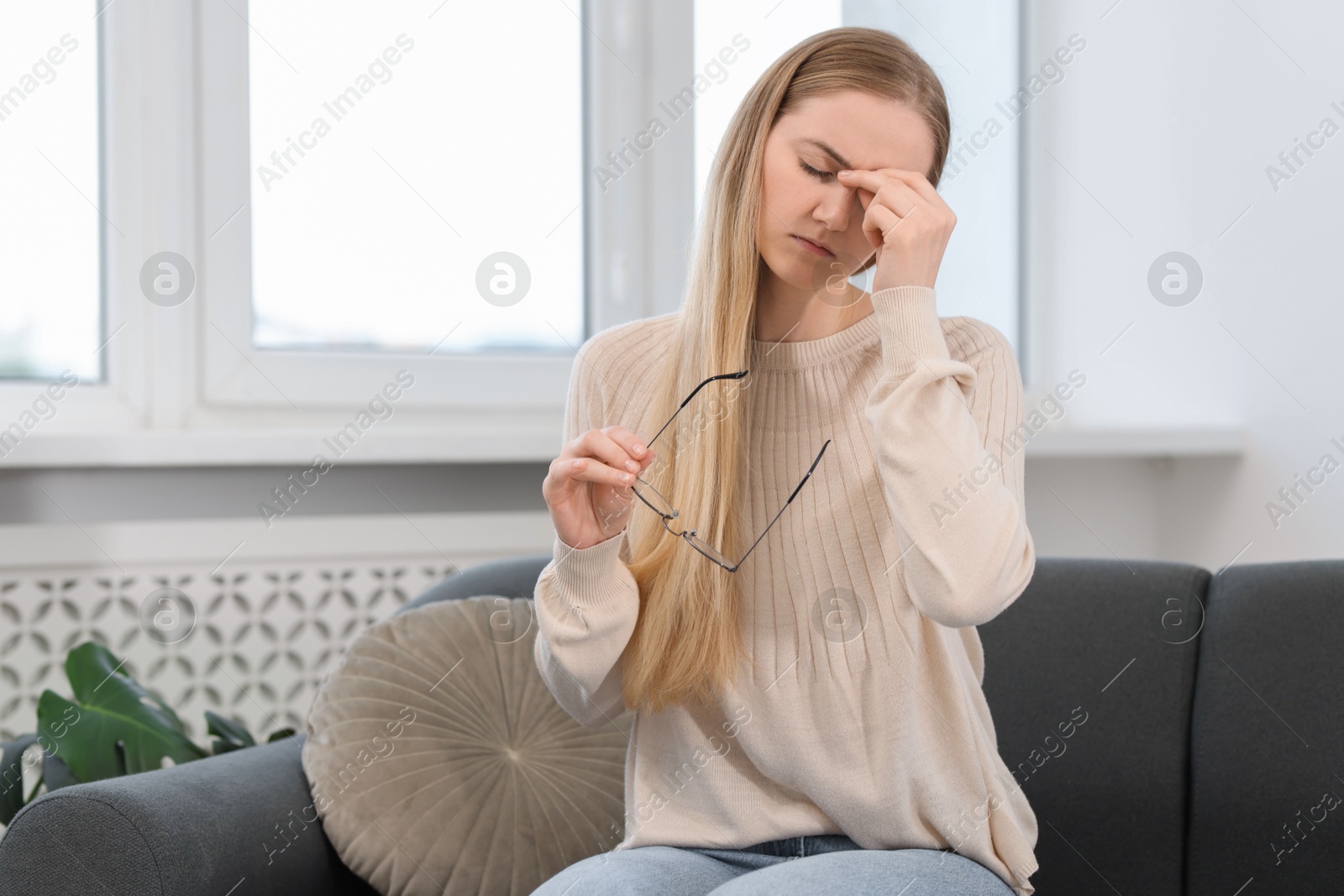 Photo of Overwhelmed young woman with glasses suffering from headache at home