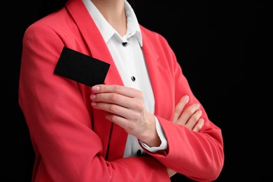 Woman holding blank business card on black background, closeup. Space for text