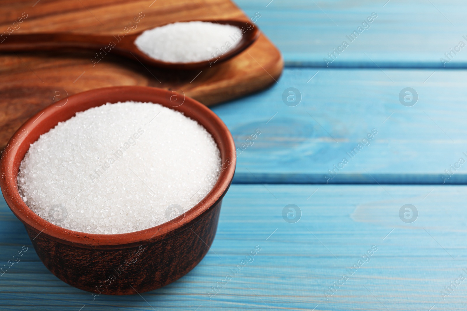 Photo of Granulated sugar on turquoise wooden table, closeup. Space for text