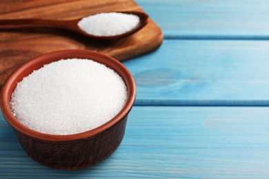 Granulated sugar on turquoise wooden table, closeup. Space for text