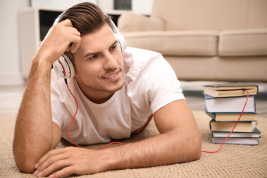Photo of Man with headphones connected to book
on floor at home. Audiobook concept