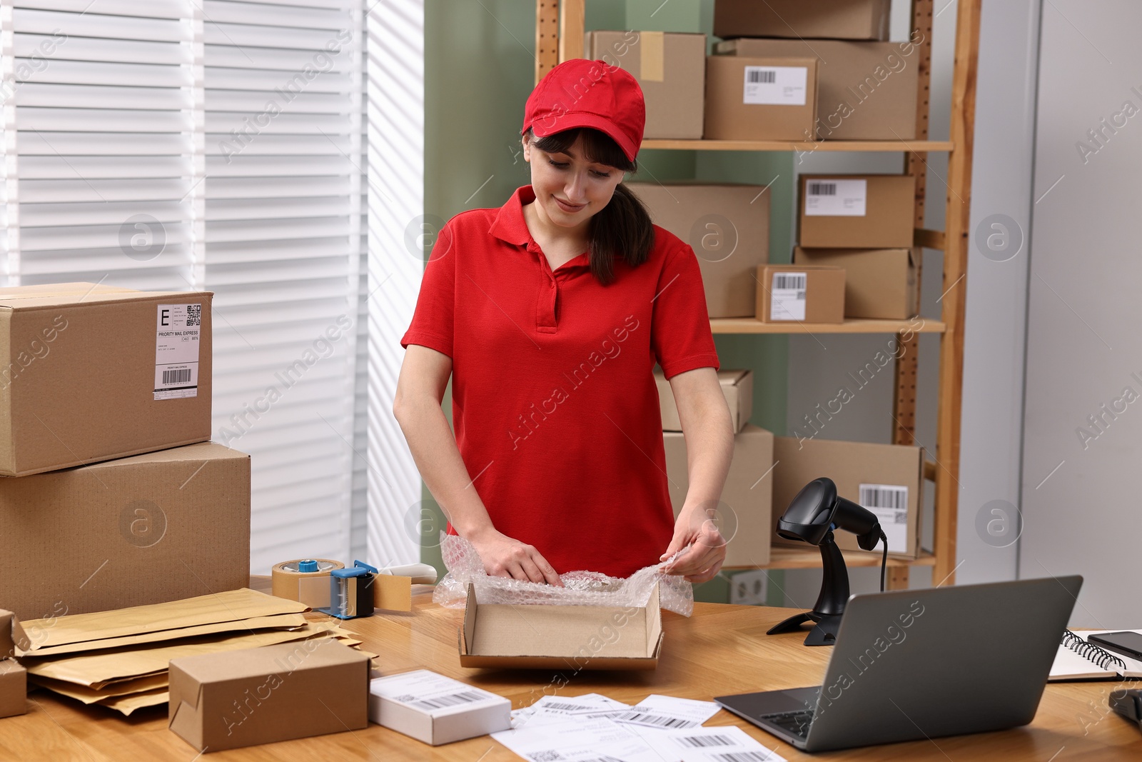 Photo of Post office worker packing parcel at wooden table indoors