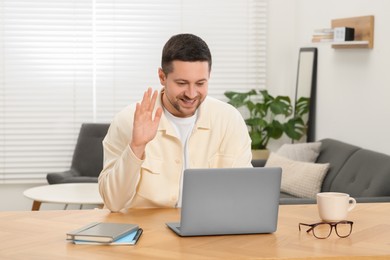 Man having video chat via laptop at wooden table at home