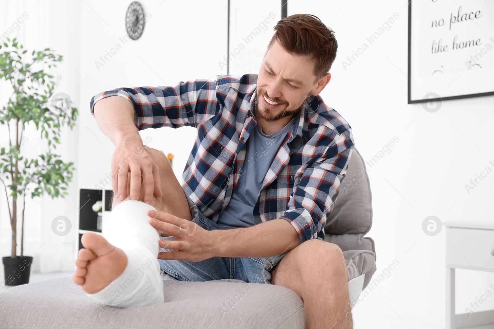 Photo of Mature man with broken leg in cast sitting in armchair at home