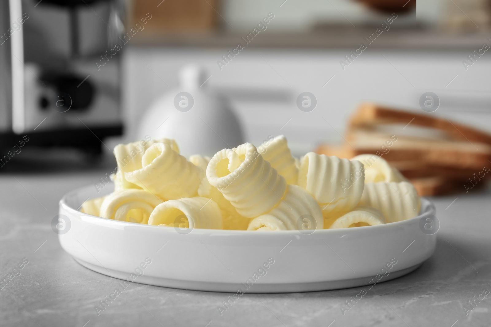 Photo of Plate with tasty butter curls on table