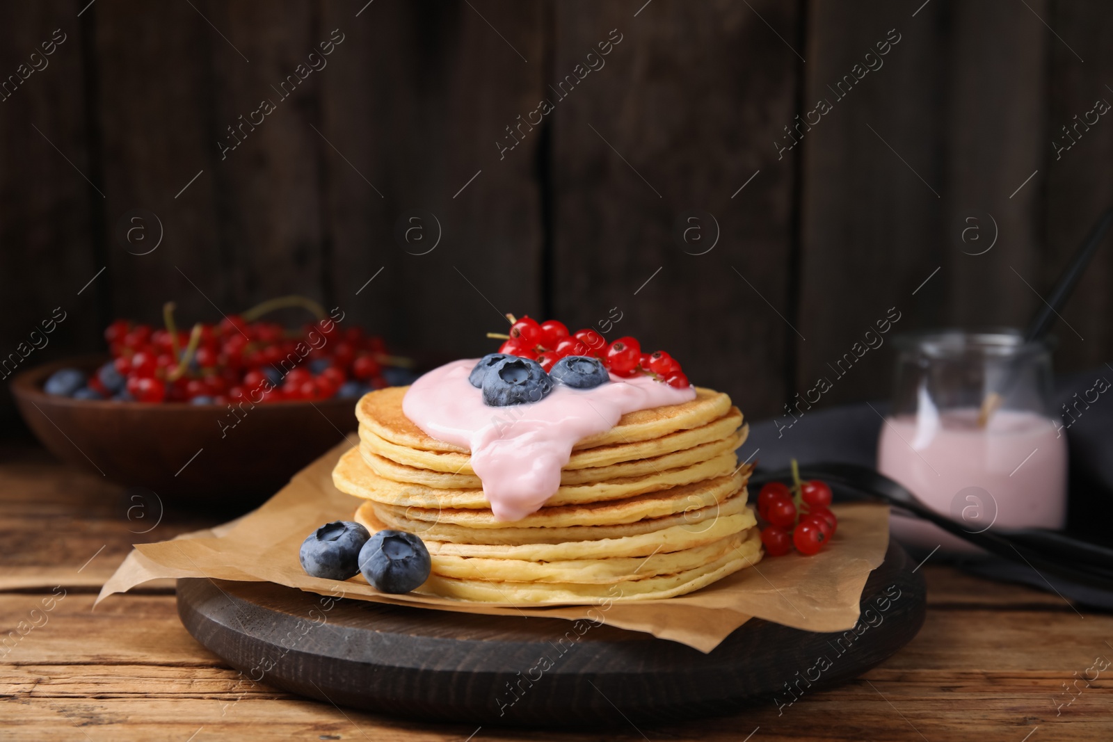 Photo of Tasty pancakes with natural yogurt, blueberries and red currants on wooden table. Space for text