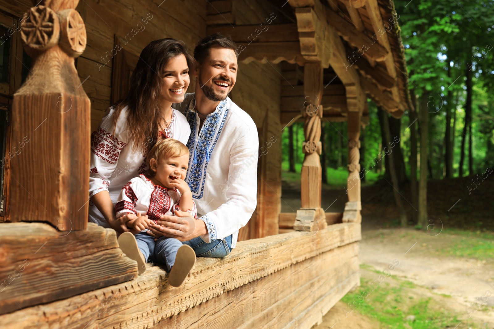 Photo of Happy family in Ukrainian national clothes on wooden terrace