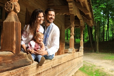 Photo of Happy family in Ukrainian national clothes on wooden terrace