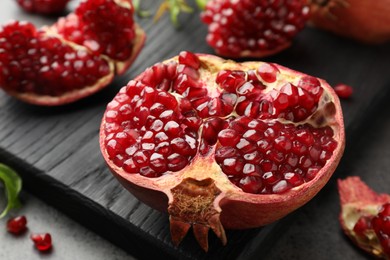 Photo of Cut fresh pomegranate on grey table, closeup