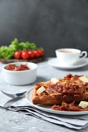 Photo of Delicious Belgium waffles served with fried bacon and butter on grey table, closeup. Space for text