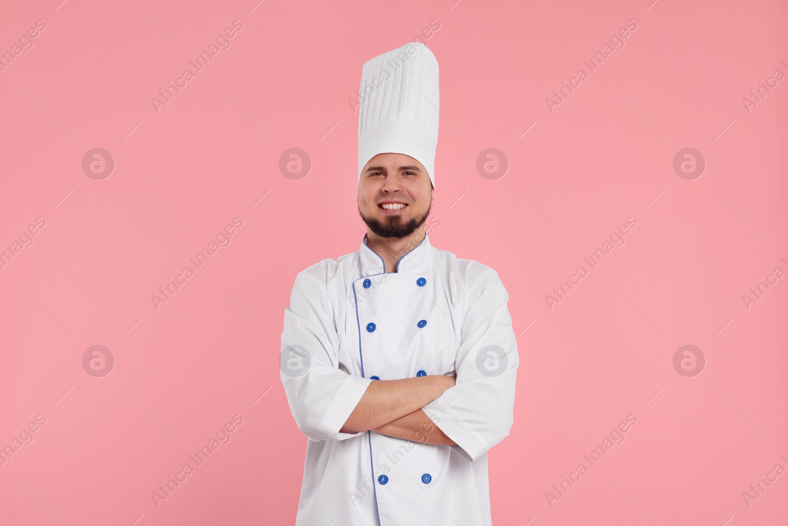 Photo of Happy professional confectioner in uniform on pink background