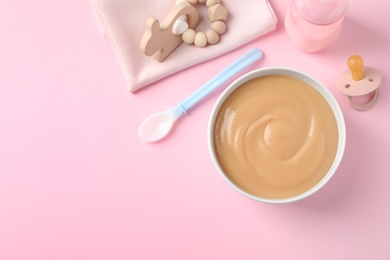 Photo of Flat lay composition with bowl of healthy baby food on pink background. Space for text