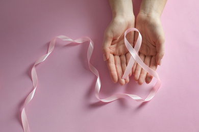 Photo of Woman holding pink ribbon on color background, top view. Breast cancer awareness
