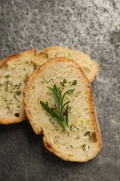 Photo of Tasty baguette with garlic, rosemary and dill on grey textured table, flat lay