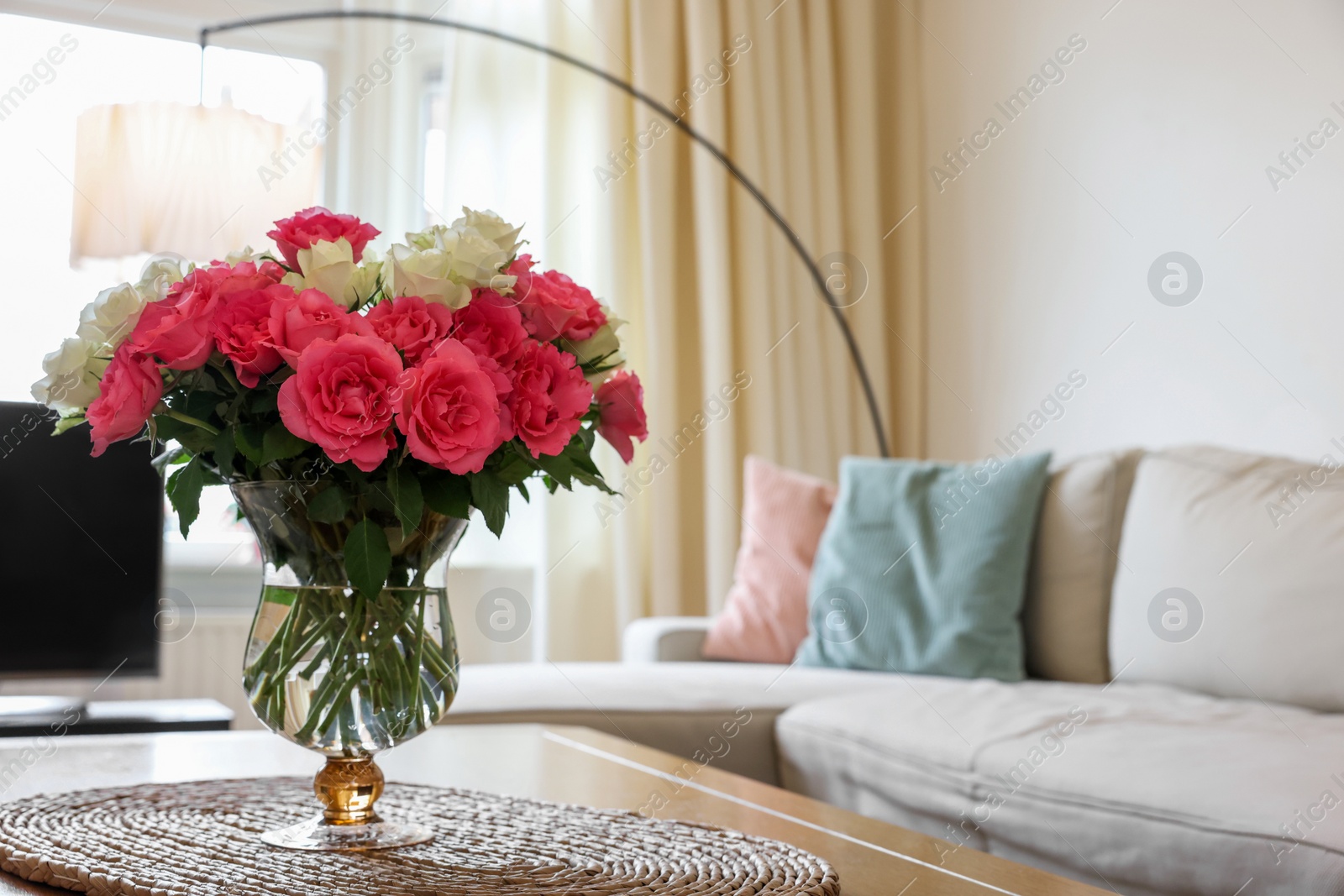 Photo of Vase with beautiful bouquet of roses on wooden table at home, space for text