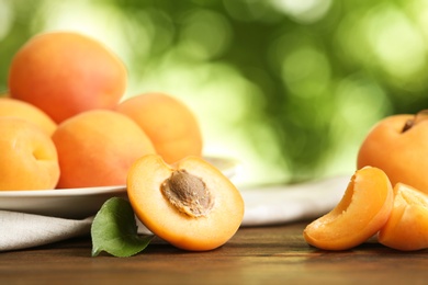 Delicious ripe sweet apricots on wooden table against blurred background, closeup view. Space for text