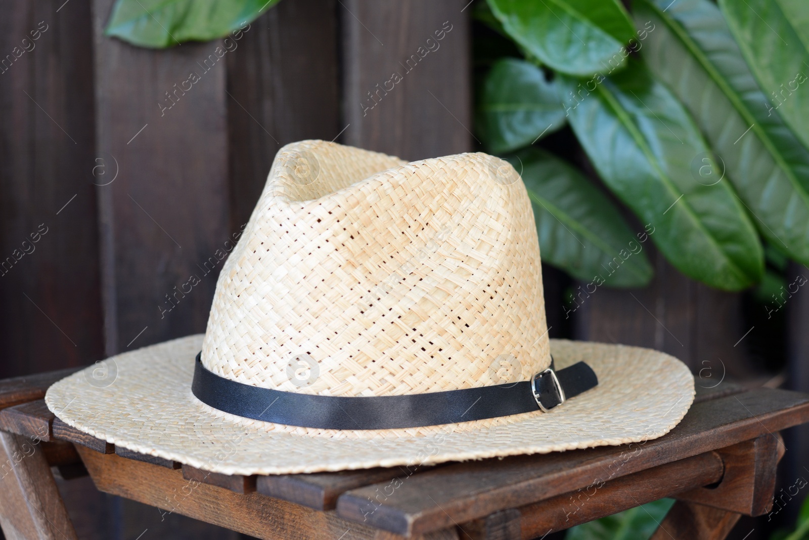 Photo of Stylish hat on wooden stool near fence. Beach accessory