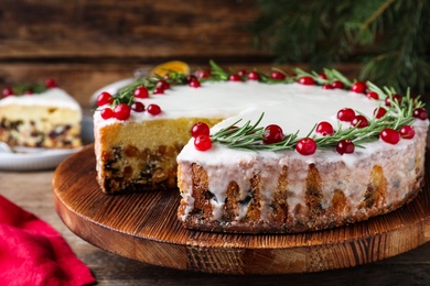 Photo of Traditional Christmas cake decorated with rosemary and cranberries on table, closeup