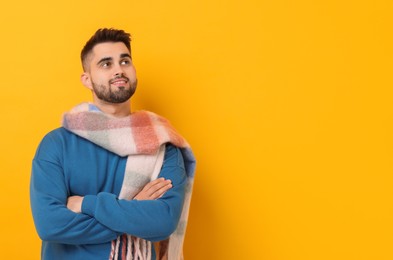 Photo of Smiling man in warm scarf on yellow background. Space for text