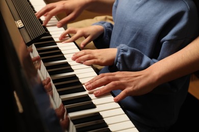 Photo of Young woman with child playing piano, closeup. Music lesson