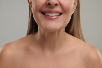 Mature woman with healthy skin on grey background, closeup