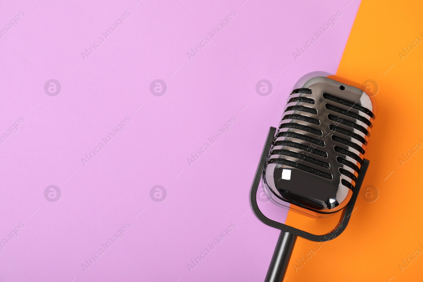 Photo of Retro microphone on color background, top view with space for text