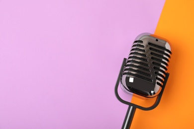 Retro microphone on color background, top view with space for text