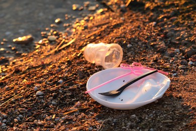 Photo of Used plastic tableware near water at beach, closeup and space for text. Environmental pollution concept