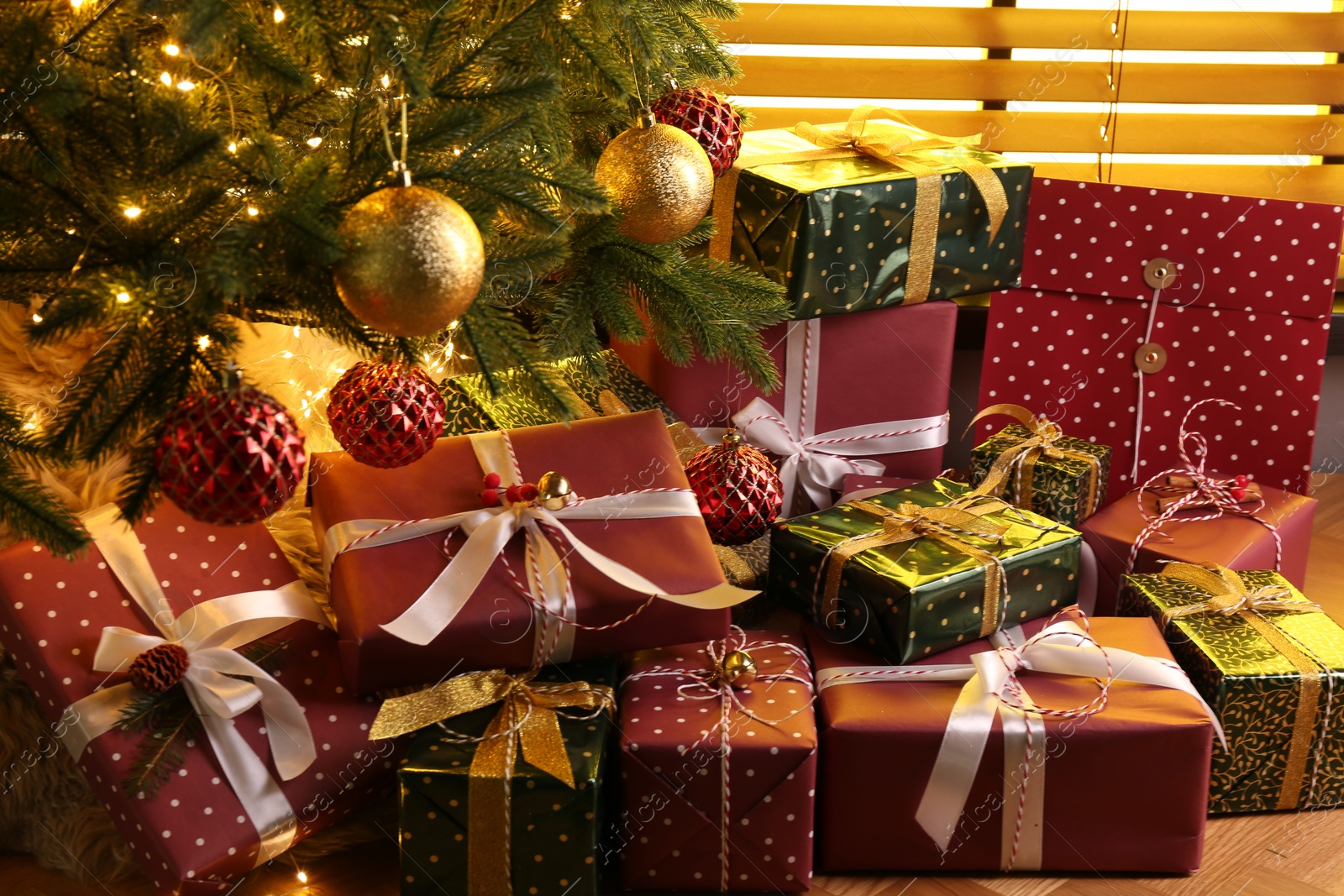 Photo of Pile of gift boxes near decorated Christmas tree indoors