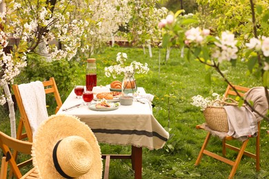 Photo of Stylish table setting with beautiful spring flowers, fruit drink and pie in garden