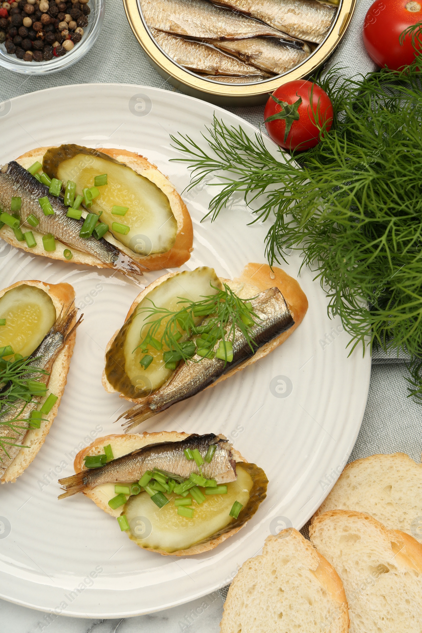 Delicious sandwiches with sprats, pickled cucumber, green onion and dill served on table, flat lay Photo of Delicious sandwiches with sprats, pickled cucumber, green onion and dill served on table, flat lay