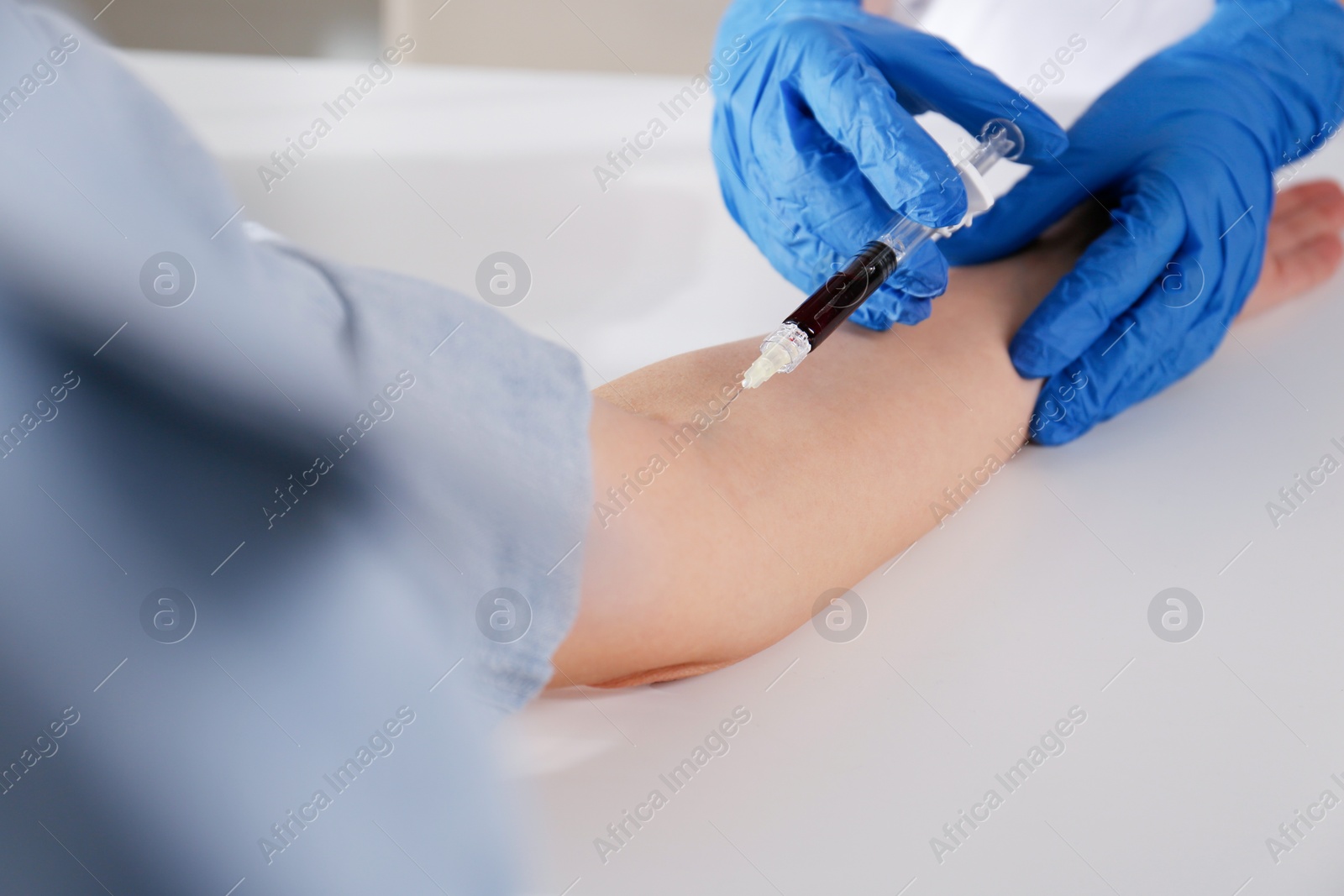 Photo of Nurse drawing blood sample from patient in clinic, closeup
