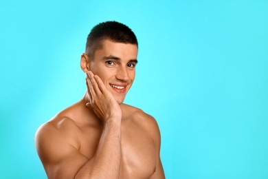 Handsome young man after shaving on light blue background, space for text