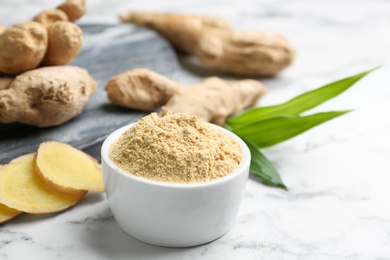 Dry ginger powder, fresh root and leaves on white marble table. Space for text