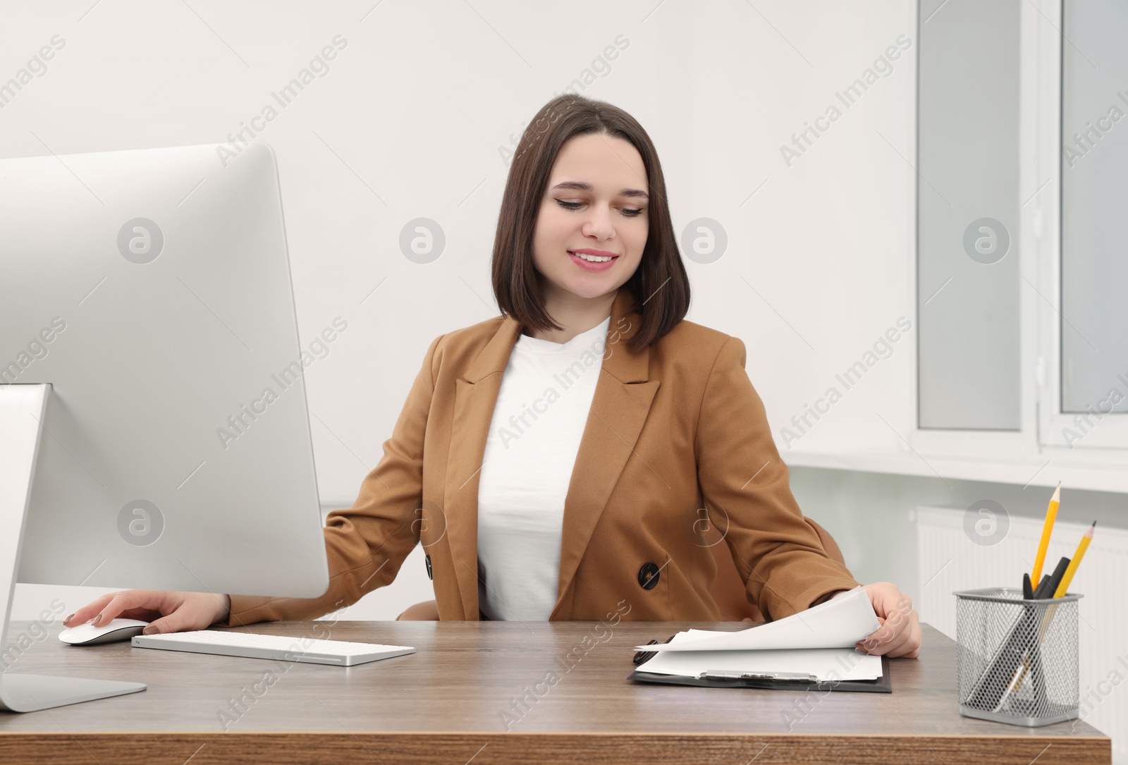 Photo of Happy young intern working at table in modern office