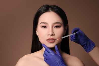 Photo of Woman getting lip injection on brown background