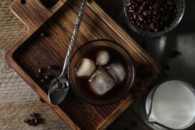 Photo of Delicious iced coffee, milk and beans on wooden table, flat lay