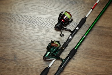 Photo of Fishing rods with spinning reels on wooden background, top view. Space for text