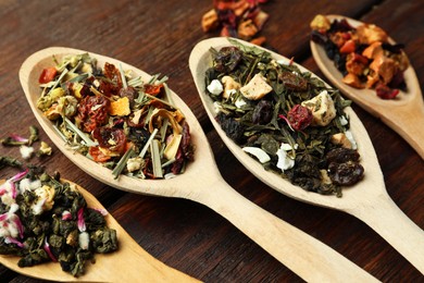 Spoons with dried herbal tea leaves on wooden table, closeup