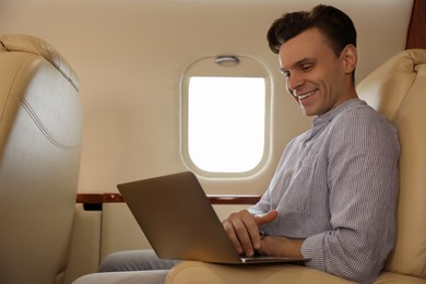 Photo of Young man using laptop in airplane during flight