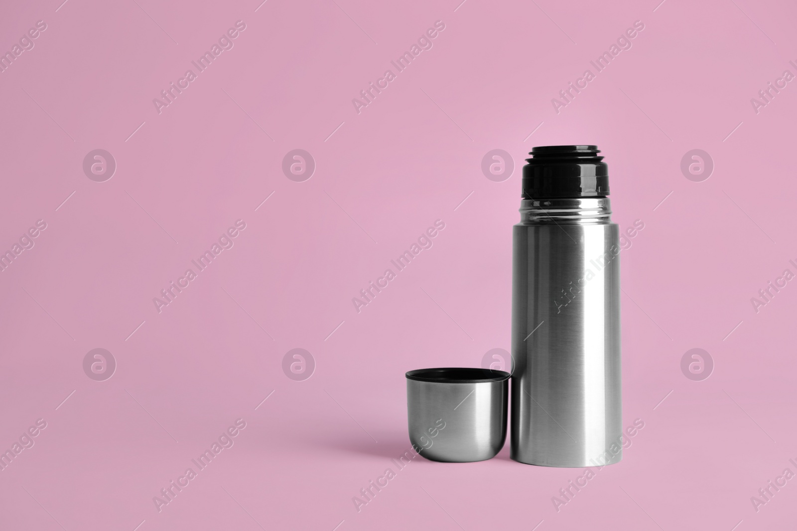 Photo of Stylish thermo bottle on pink background, space for text