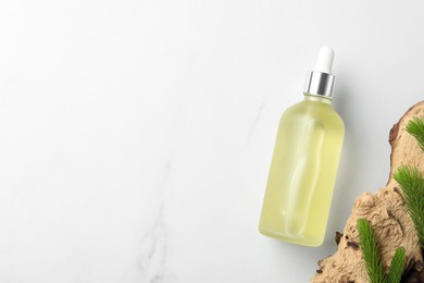 Photo of Bottle of hydrophilic oil near tree bark with fir twigs on white background, flat lay. Space for text