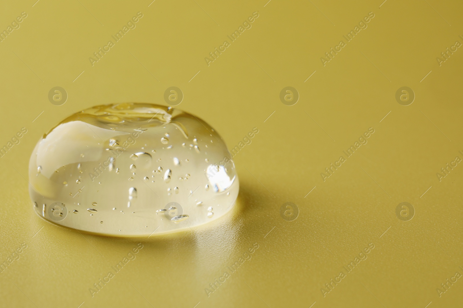 Photo of Sample of clear cosmetic gel on yellow background, closeup. Space for text