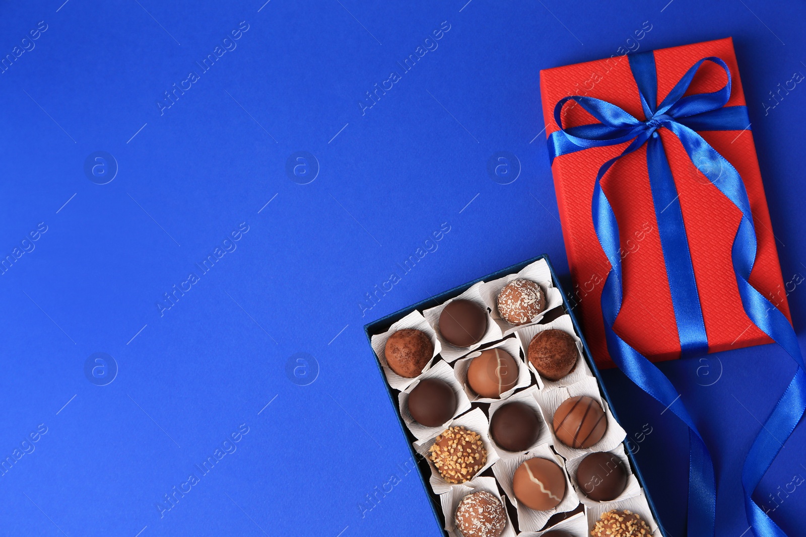 Photo of Box with delicious chocolate candies on blue background, flat lay. Space for text