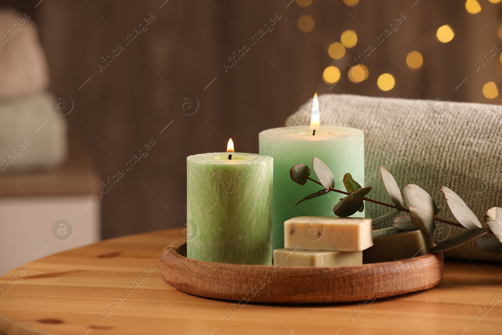 Photo of Spa composition. Burning candles, soap, towel and eucalyptus branch on wooden table, space for text