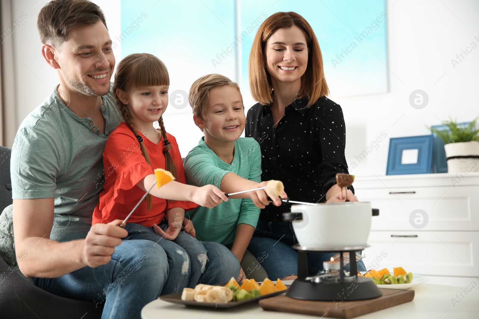 Photo of Happy family enjoying fondue dinner at home