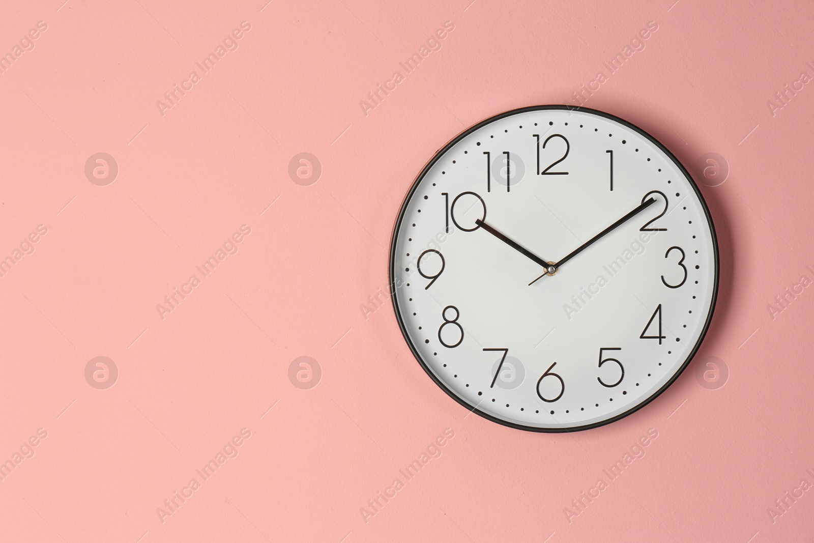 Photo of Stylish analog clock hanging on color wall. Space for text