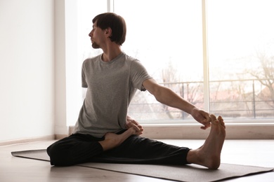 Photo of Young man practicing yoga indoors
