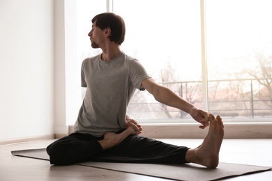 Young man practicing yoga indoors