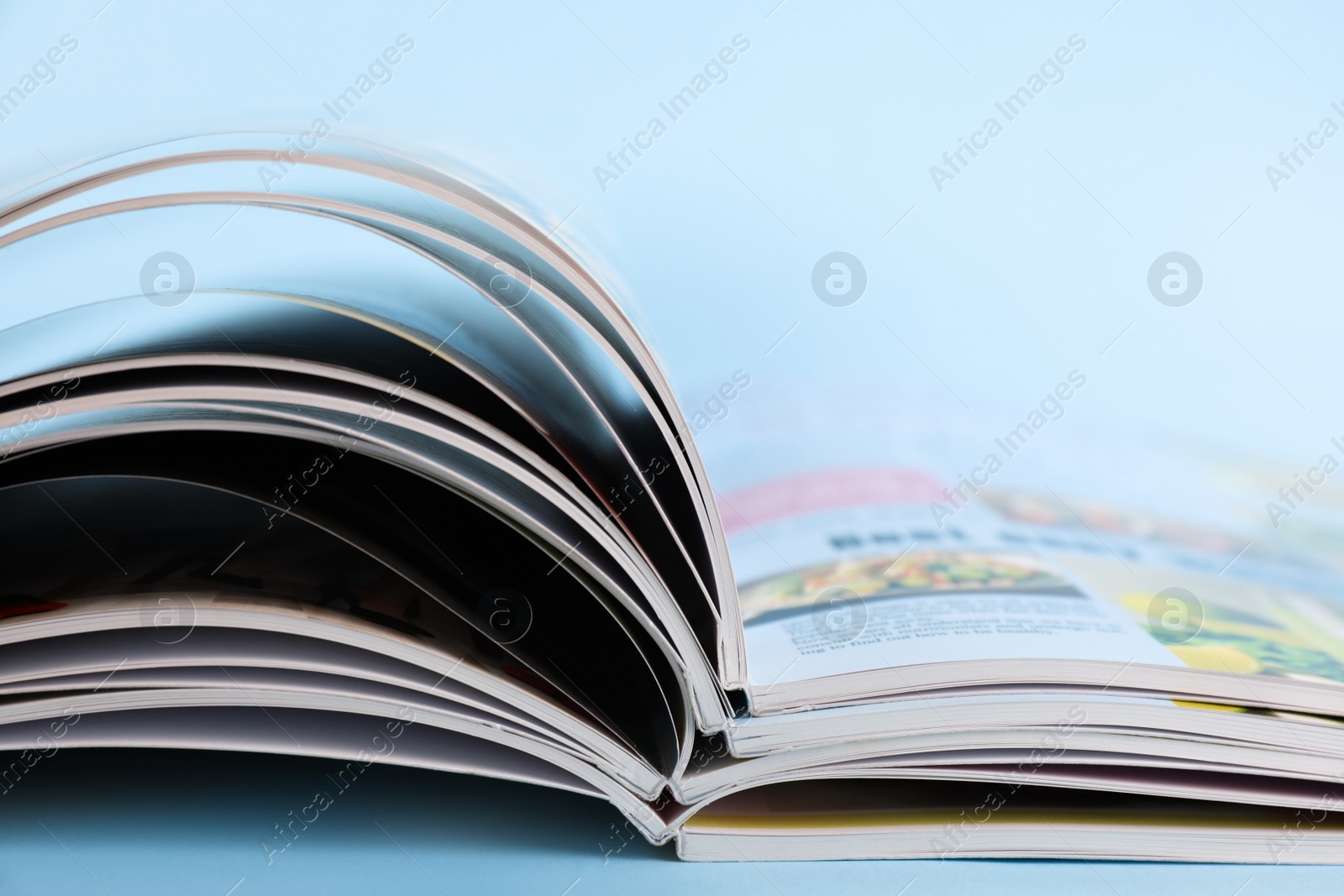 Photo of Stack of magazines on light blue background, closeup